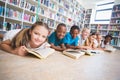 Smiling school kids lying on floor reading book in library Royalty Free Stock Photo