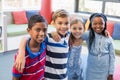 Smiling school kids standing with arm around in library Royalty Free Stock Photo