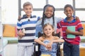 Smiling school kids standing with arm around in library Royalty Free Stock Photo