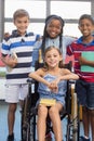 Smiling school kids standing with arm around in library