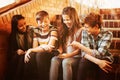 Smiling school students sitting on the staircase using mobile phone Royalty Free Stock Photo