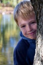 Smiling schoolboy behind a tree