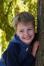 Smiling schoolboy behind a tree