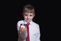 Smiling schoolboy with a red alarm clock in his hands. Morning concept. Black background