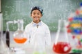 Smiling schoolboy standing in classroom with chemical flask in foreground Royalty Free Stock Photo