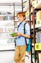 Smiling schoolboy stands and holds books