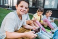 smiling schoolboy using tablet while sitting on grass