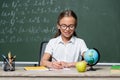 smiling schoolgirl in eyeglasses writing in Royalty Free Stock Photo