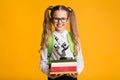 Smiling Schoolgirl Holding Book Stack And Microscope, Yellow Background