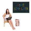 Smiling schoolgirl with a huge pile of books and a laptop in front of a blackboard Royalty Free Stock Photo