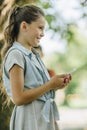 Smiling schoolgirl smiling while looking away while using smartphone in park Royalty Free Stock Photo