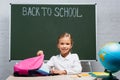 Smiling schoolgirl taking books from backpack