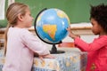 Smiling schoolgirls looking at a globe Royalty Free Stock Photo