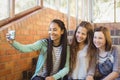 Smiling schoolgirls sitting on the staircase taking selfie with mobile phone Royalty Free Stock Photo