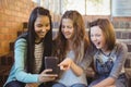 Smiling schoolgirls sitting on the staircase using mobile phone Royalty Free Stock Photo