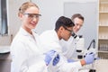 Smiling scientist looking at camera while colleagues working with microscope