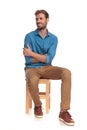 Smiling seated young casual man looks to side