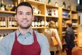 Smiling seller man wearing apron in wine store