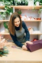 Smiling seller packing gift box in wrapping paper