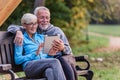 Smiling senior active couple sitting on the bench looking at tablet computer Royalty Free Stock Photo