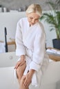 Smiling senior adult lady sitting at spa center. Ads of spa procedures. Royalty Free Stock Photo