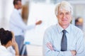 Smiling senior business man with executives. Portrait of smiling senior business man with executives in background at Royalty Free Stock Photo