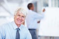 Smiling senior business man at office. Portrait of senior business man smiling with male executive in background. Royalty Free Stock Photo