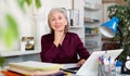 Smiling senior business woman working on laptop in office