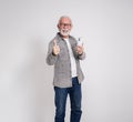 Smiling senior businessman messaging over smart phone and showing thumbs up on white background