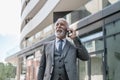 Smiling businessman talking on smart phone while standing outside the office building Royalty Free Stock Photo