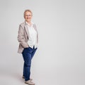 Smiling senior businesswoman with hands in pockets posing confidently on isolated white background Royalty Free Stock Photo