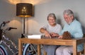 Smiling senior couple doing a jigsaw puzzle at home on wooden table. Vintage bicycle in the corner Royalty Free Stock Photo