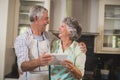 Smiling senior couple holding digital tablet while standing in kitchen Royalty Free Stock Photo