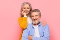 Smiling senior couple hugging posing for portrait against pink backdrop Royalty Free Stock Photo