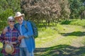 Smiling senior couple hugging walking in the forest, between green meadow and trees. Two happy retired enjoying healthy lifestyle Royalty Free Stock Photo