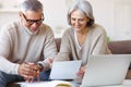 Smiling senior couple reading notification letter with good news from bank while sitting with laptop Royalty Free Stock Photo