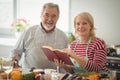 Smiling senior couple with recipe book standing in kitchen Royalty Free Stock Photo
