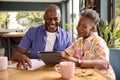 Smiling Senior Couple Sitting Around Table At Home Reviewing Finances Using Digital Tablet Royalty Free Stock Photo