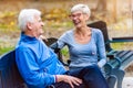 Smiling senior couple sitting in the park talking