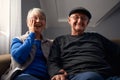 Smiling Senior Couple Sitting On Sofa At Home Watching Television Together Royalty Free Stock Photo