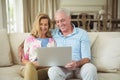 Smiling senior couple using laptop in living room Royalty Free Stock Photo