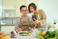 Smiling senior couple using smart mobile phone together while cooking in kitchen. Royalty Free Stock Photo