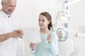 Smiling senior dentist giving toothbrushes and medical report to patient