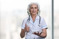 Smiling senior doctor using transparent digital tablet and showing thumb up gesture. Royalty Free Stock Photo