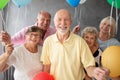 Smiling senior friends with colorful balloons in dark interior with concrete wall Royalty Free Stock Photo