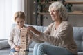 Happy senior grandmother and granddaughter play wooden stack game