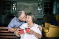 Smiling senior husband making surprise giving gift to his wife