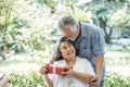 Smiling senior husband making surprise giving gift to his wife