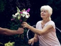 Elderly woman get a beautiful bouquet of field flowers. Royalty Free Stock Photo