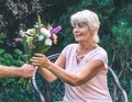 Elderly woman get a beautiful bouquet of field flowers. Royalty Free Stock Photo